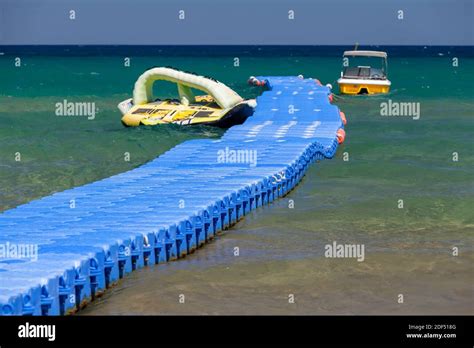 Blue Plastic Floating Pier With Moored Motor Boats Beach At Greek