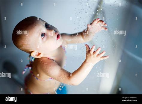 Ein kleines Mädchen in einem Badeanzug steht in der Dusche schaut auf