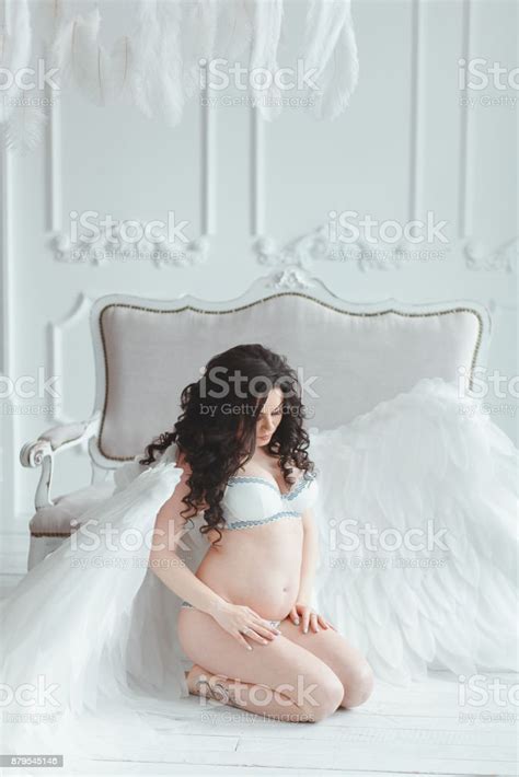 Beautiful Young Pregnant Girl With Big Angel Wings In White Studio
