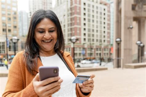 Premium Photo Mature Indian Woman Holding Credit Card And Mobile Phone Receive Payment