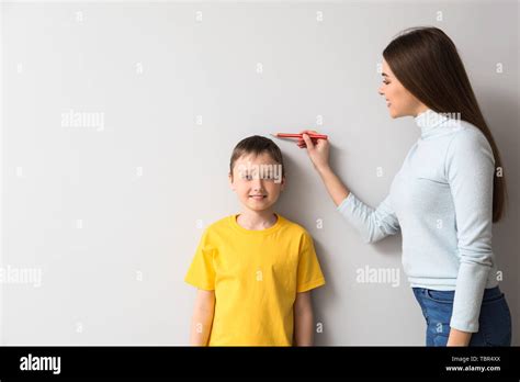 Mother Measuring Height Of Her Son Near Wall Stock Photo Alamy