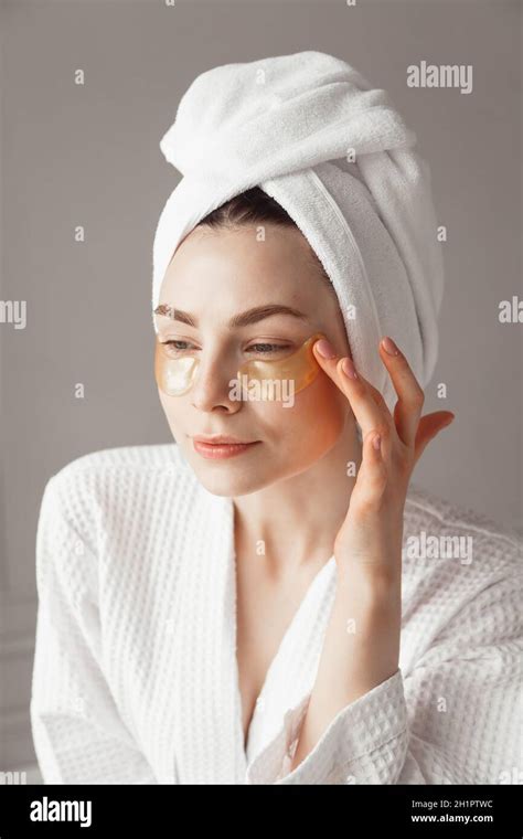 Pretty European Girl Applying Golden Collagen Patches Under Her Eyes