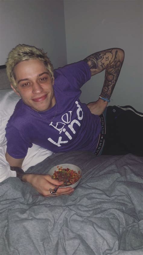 A Man Laying In Bed With A Bowl Of Food On His Lap And Smiling At The Camera
