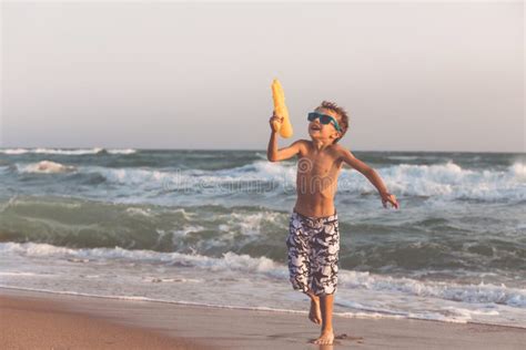 Um Rapaz Pequeno Feliz Que Joga Na Praia No Tempo Do Dia Imagem De