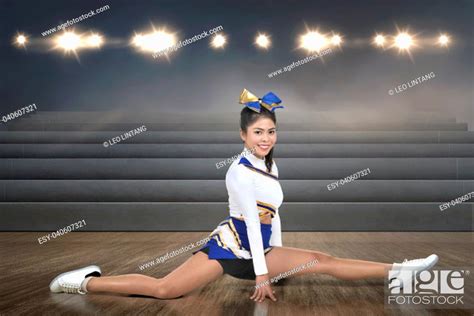 Smiling Asian Cheerleader Doing Splits At Indoor Arena Stock Photo