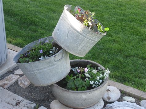 Three Metal Buckets Are Stacked On Top Of Each Other With Flowers