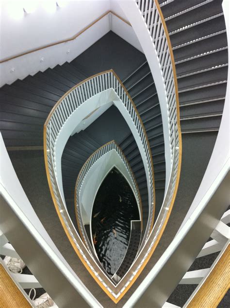 A Spiral Staircase In A Building With People Walking Down It