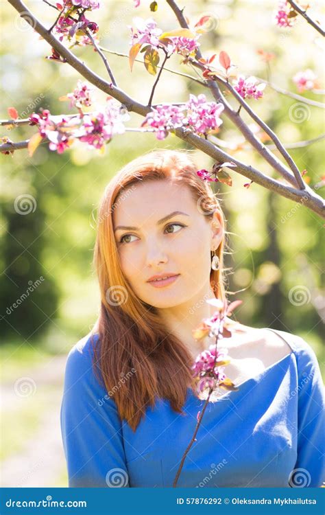 Beautiful Young Red Haired Girl In Blue Dress Among Spring Flowe Stock
