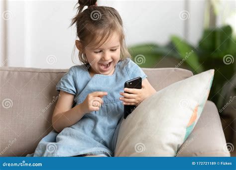 Overjoyed Little Preschool Kid Girl Playing Online Game On Smartphone