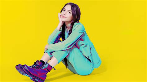 Olivia Rodrigo Is Wearing Green Coat Suit Sitting In Yellow Background