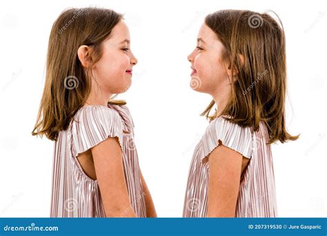 Identical Twin Girls Are Looking At Each Other And Smiling Stock Photo