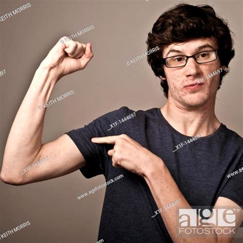 A Weak Feeble Geek Nerd Youn Man With Thin Arms Wearing Glasses Flexing