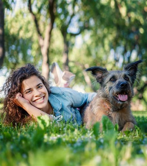 Young Joyful Smiling Curly Beautiful Woman With Her Dog In The Park On