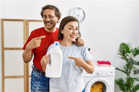 Middle Age Interracial Couple Doing Laundry Holding Detergent Bottle