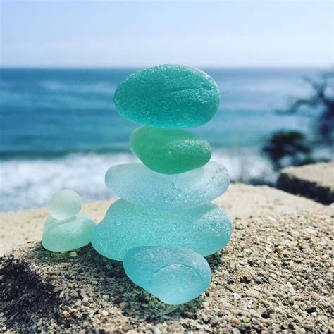 A Stack Of Sea Glass Sitting On Top Of A Rock