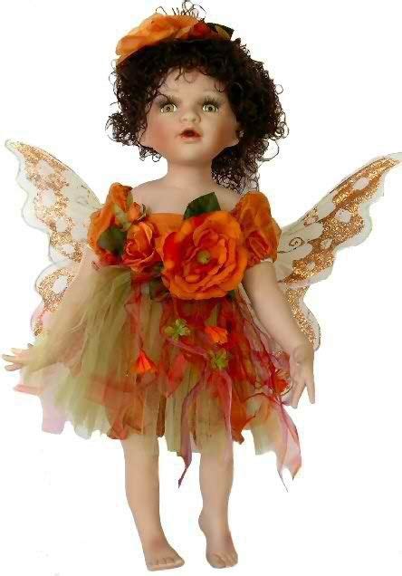 A Doll Dressed In Orange And Green With Flowers On Her Wings Holding A
