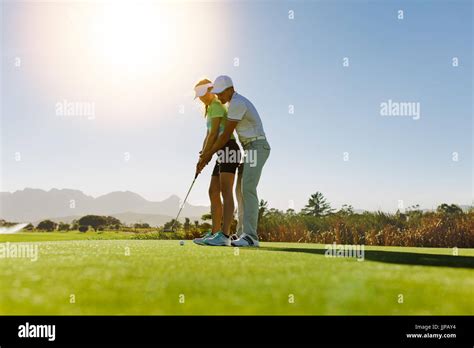 Man Teaching Woman To Play Golf While Standing On Field Personal