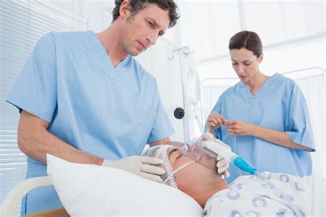 Doctors Holding Oxygen Mask And Examining Intravenous Drip Stock Image