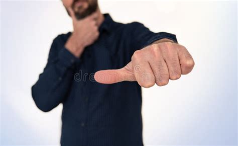 Man In Blue Shirt Doing Hand Gesture With Thumb Sideways Stock Image
