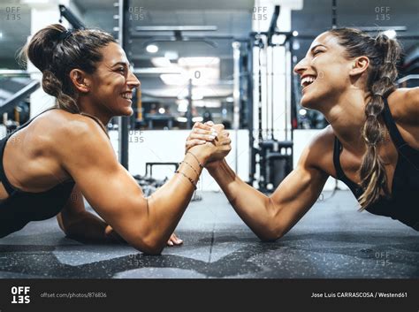 Happy Female Twins In Good Shape Doing Arm Wrestling Challenge In A Gym