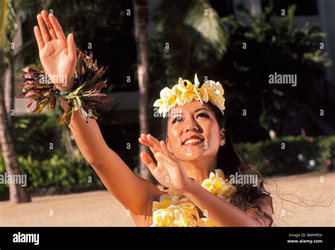 a hula dancer tells a traditional native story with her hands as she performs on waikiki beach