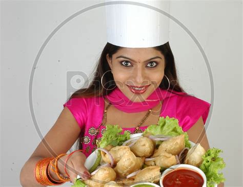 Image Of An Indian Woman Chef In Kitchen Apron And Cap Holding Samosas Plate With An Expression