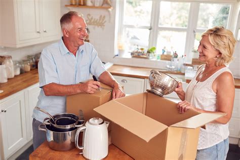 Senior Couple Downsizing In Retirement Packing And Labelling Boxes
