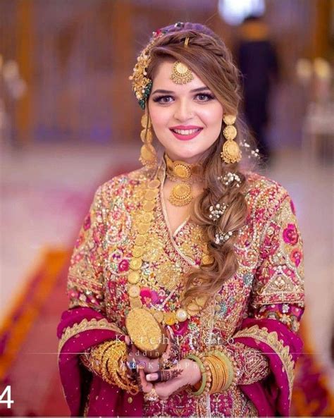 a woman in a red and gold bridal outfit smiles at the camera while wearing jewelry