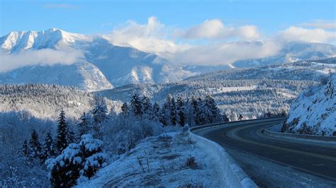 Empty Road Through Snowy Mountains In Winter The Rocky Mountains In