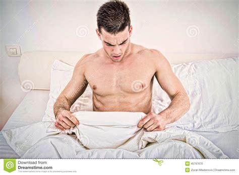 Half Naked Young Man In Bed Looking Down At His Underwear