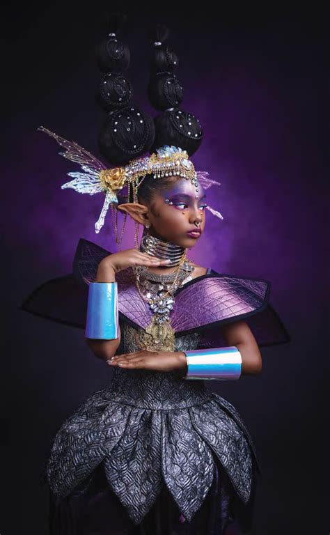 an african woman in purple and black clothing with feathers on her head holding a blue tube