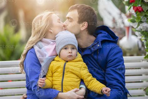 lycklig familj mamma pappa och liten son en kvinna och en man kyss och håll en små barn i deras