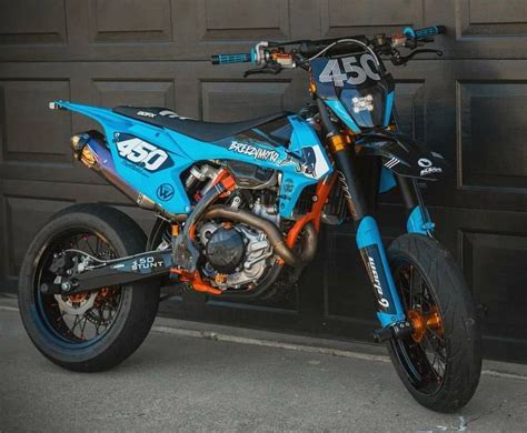 A Blue Dirt Bike Parked In Front Of A Garage Door With The Number 350 On It