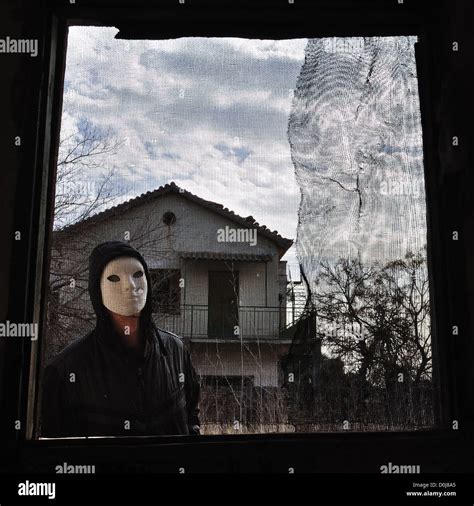 Hooded Figure Behind Threaded Window Of Derelict House Masked Maniac