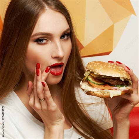 Portrait Of Playful Beautiful Sexy Woman With Red Lips Holding Delicious Hamburger And Looking