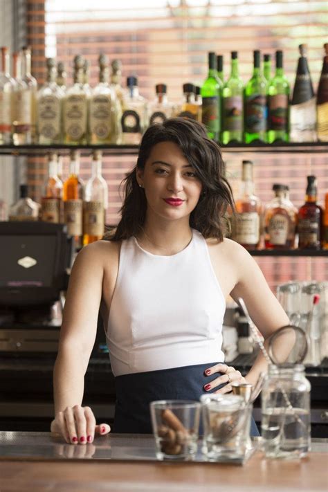 A Woman Standing In Front Of A Bar Filled With Liquor Bottles