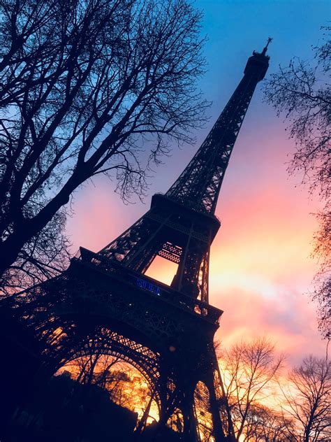 The Eiffel Tower Is Silhouetted Against An Orange And Blue Sky At Sunset