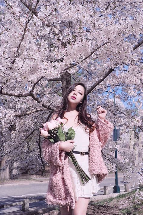 A Woman Standing In Front Of A Tree With Flowers