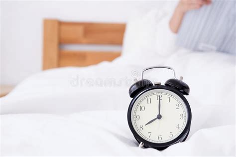 beautiful asian woman laying and reading book in bed sleep behind alarm clock stock image