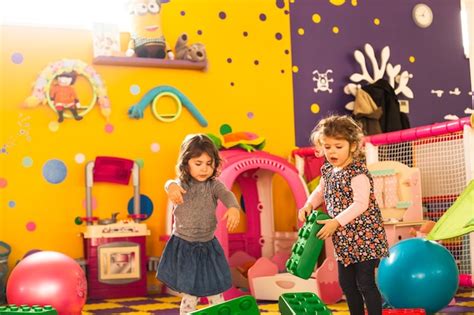 Premium Photo Two Girls Play With Big Bricks In Playroom