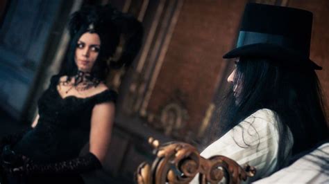 vampire couple on a masquerade girl is dressed in a black victorian gothic bustle dress and fancy