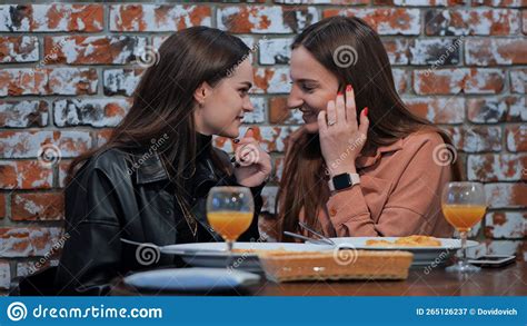 Young And Cheerful Girls Gossip And Whisper To Each Other While Sitting In A Cafe Stock Image