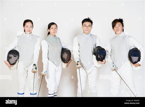Portrait Of Two Male And Two Female Fencers Holding Fencing Masks With Fencing Foils Stock Photo