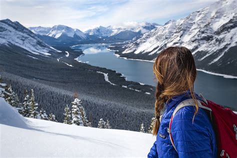 A Woman Standing On Top Of A Snow Covered Slope Looking Out Over A Lake