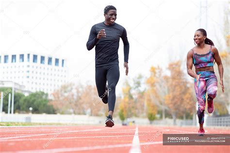 Happy Male And Female Sportsperson Running On Track Against Clear Sky — Motion People Stock