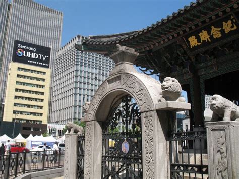 A Gate With Two Lions On It In Front Of Some Buildings