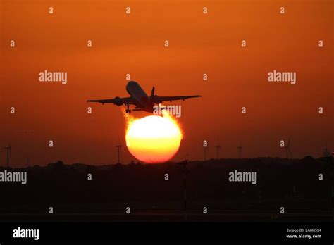 Plane Taking Off Into The Sunset With A Few Windturbines In The