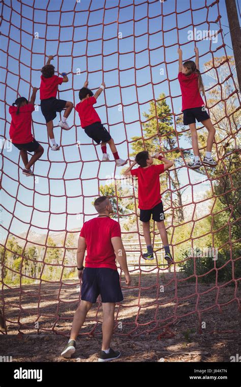 Trainer Instructing Kids In Net Climbing During Obstacle Course