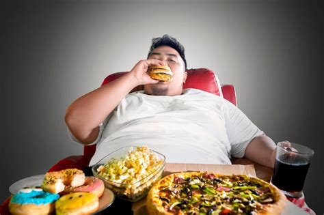 Premium Photo Fat Man Looks Greedy With Junk Foods On The Sofa