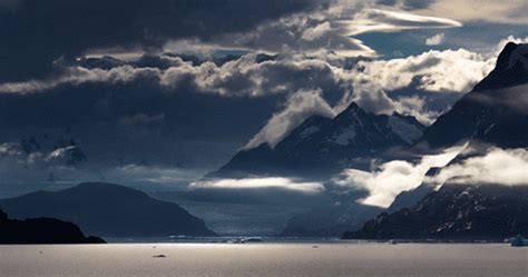 The Mountains Are Covered In Clouds As They Float Through The Water On